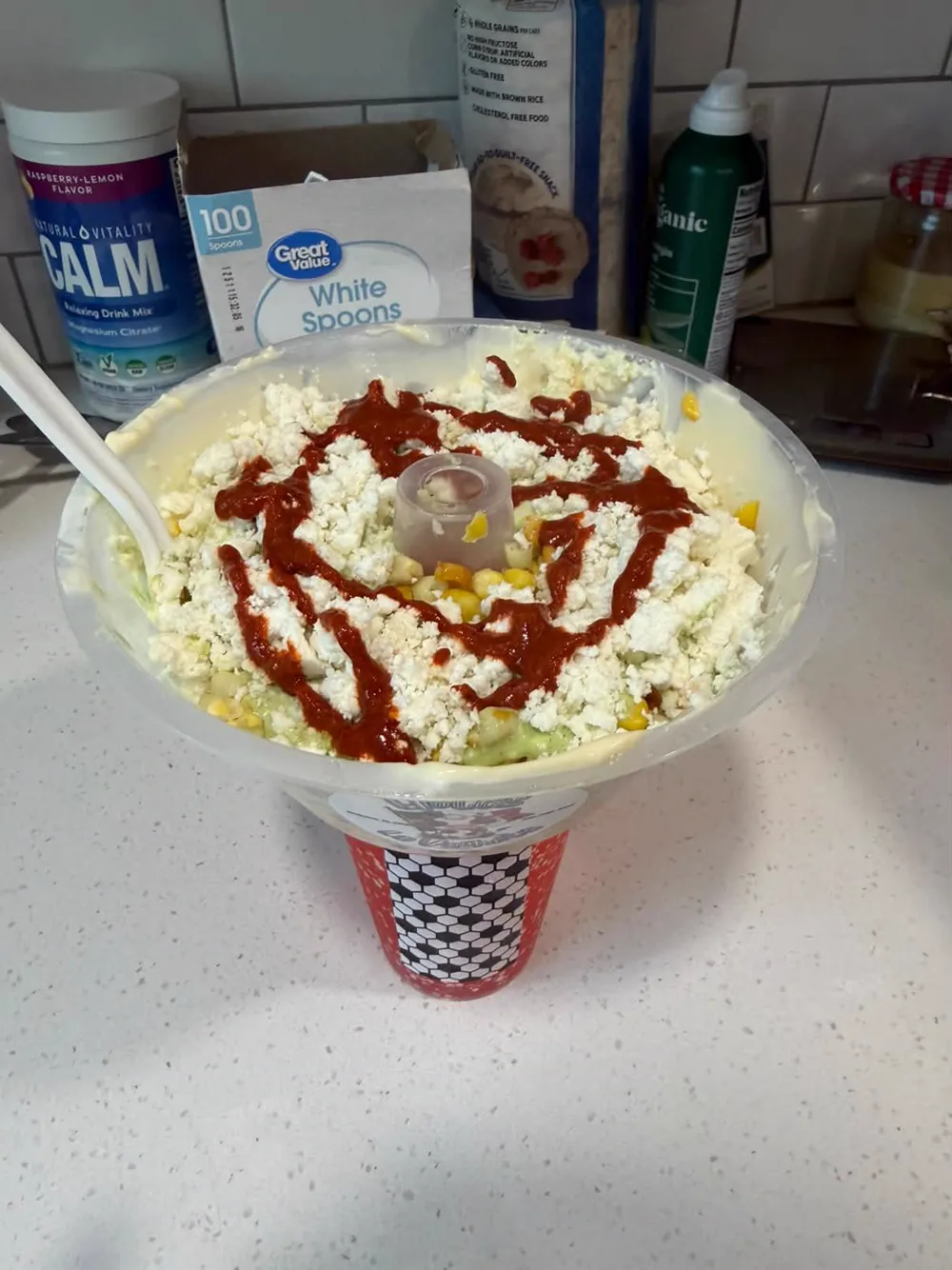 Elote cup with queso fresco and red drizzle