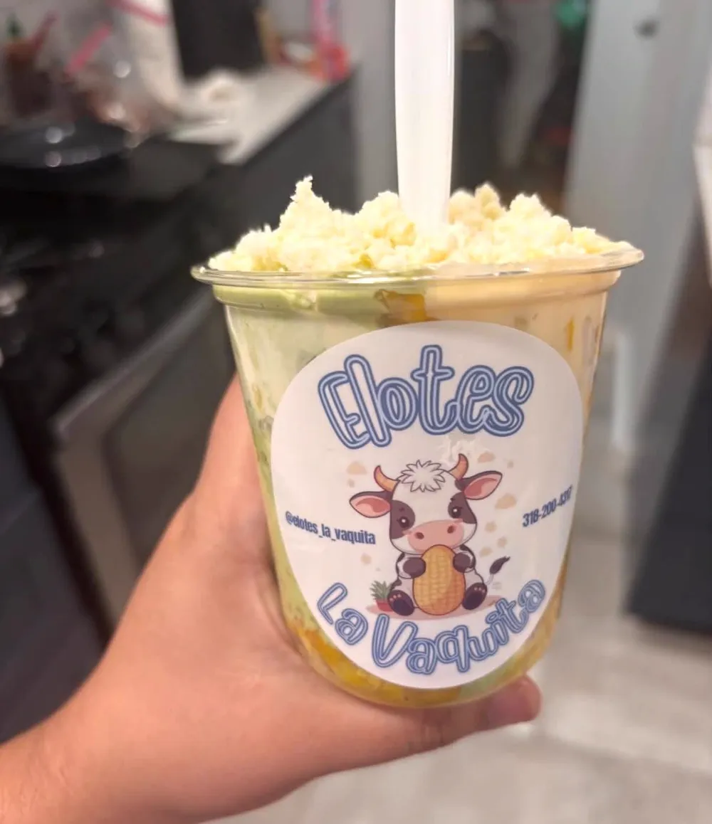 A cup of elote topped with queso fresco and a La Vaquita label